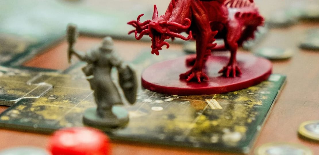 A dragon miniature facing off against an adventure miniature.